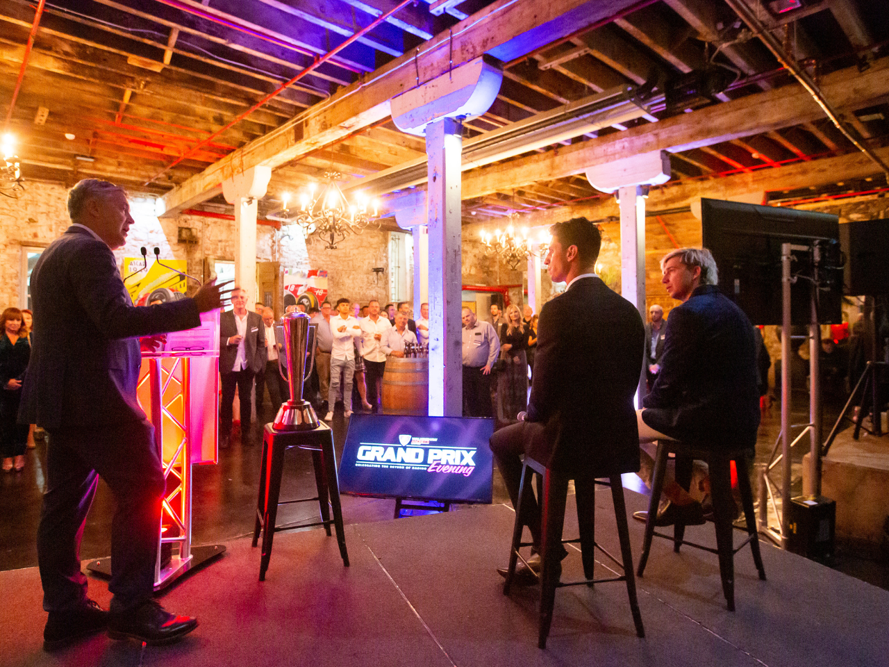 Image of speakers on stage with guests watching